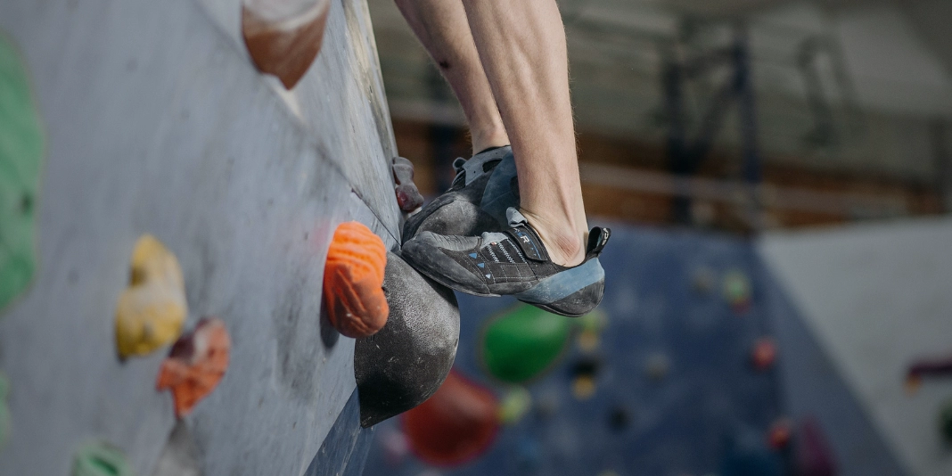 Climber switching feet on climbing hold